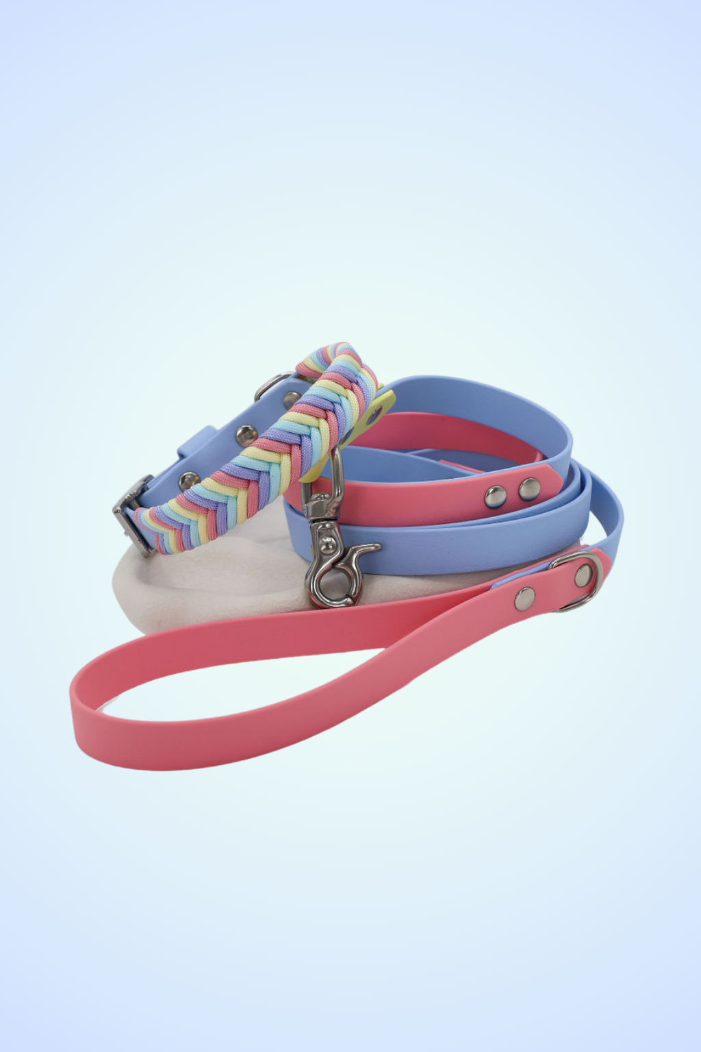 A multicolored paracord striped dog collar with a stainless steel buckle and pink and blue biothane dog lead
