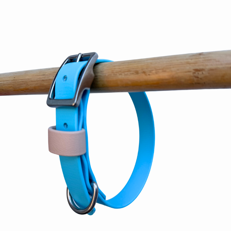 Light Blue and sand Biothane dog collar on a wooden rod against a white background.